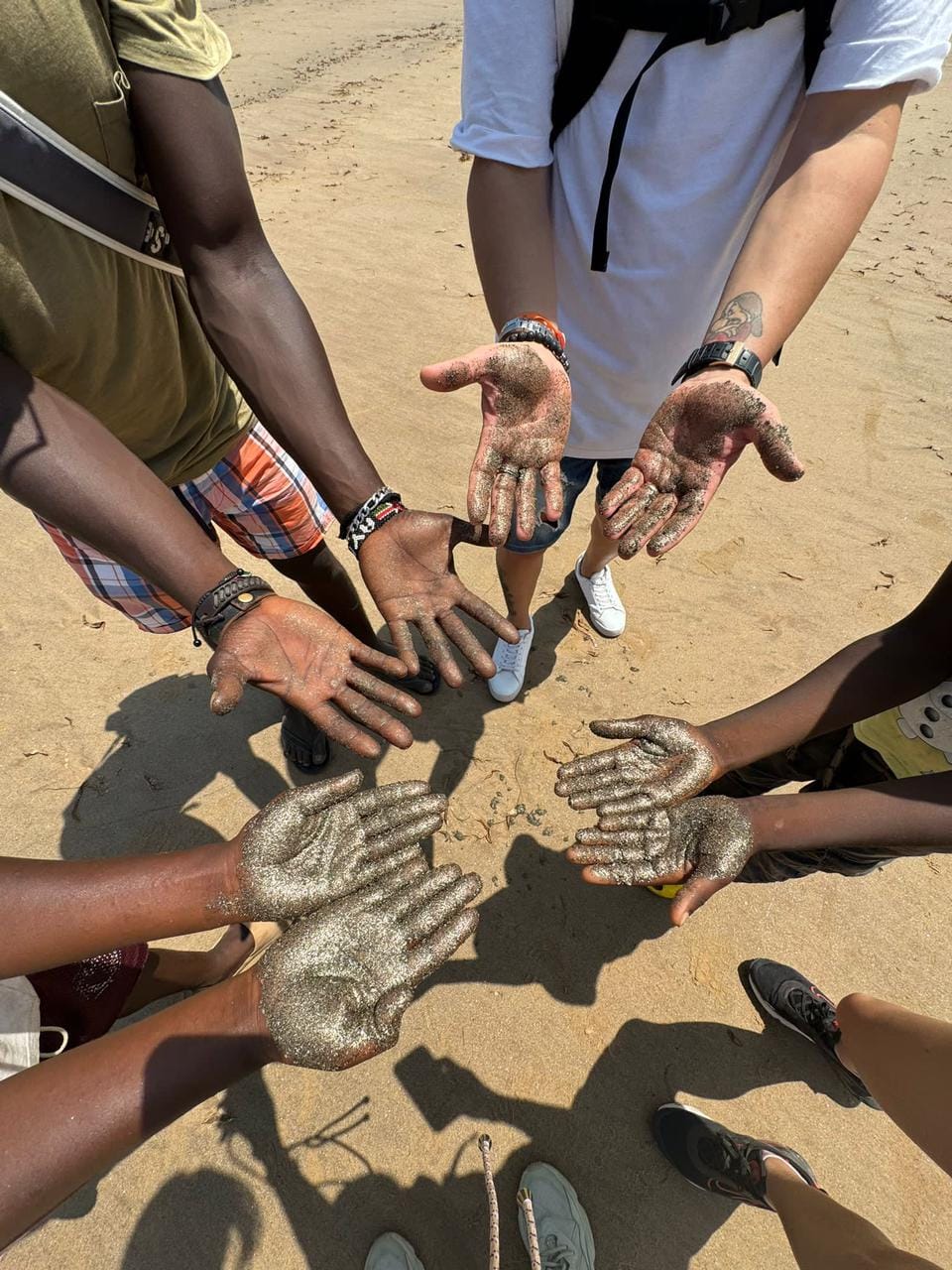 Mani dei viaggiatori sulla sabbia di Spiaggia Dorata